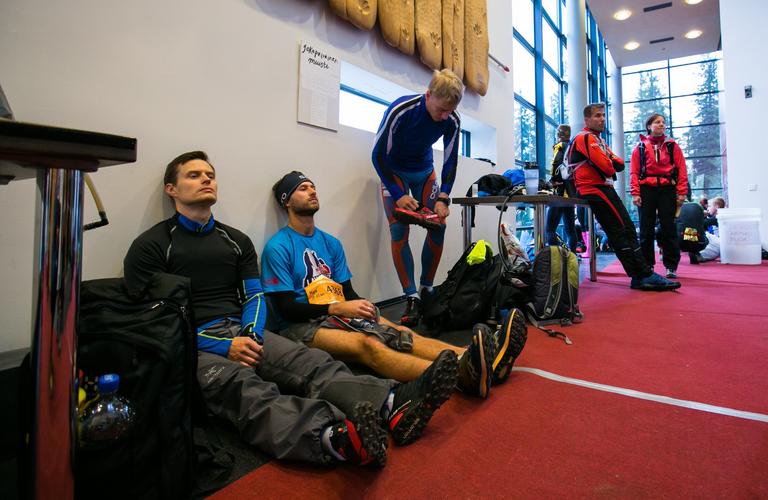 Vaarojen Maratonin osallistujat lep&auml;&auml;m&auml;ss&auml; sis&auml;tiloissa, juoksuvarusteet ymp&auml;rill&auml;&auml;n ja tunnelma on j&auml;nnittynyt..