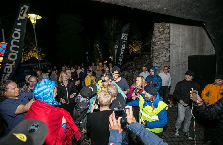 Atmosphere at the Vaarojen Ultra event, where runners and spectators have gathered on a dark trail illuminated by headlamps in Koli National Park.